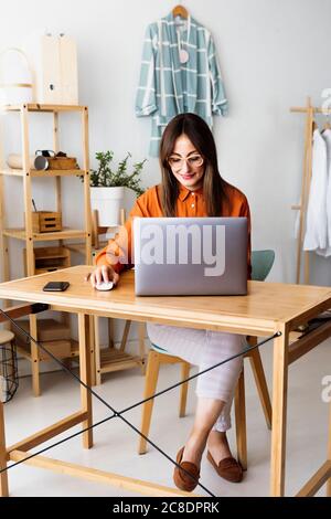 Femme de créateur de mode travaillant à la maison assis au bureau avec ordinateur portable Banque D'Images