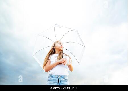 Fille tenant un parapluie tout en se tenant contre le ciel nuageux pendant la mousson Banque D'Images