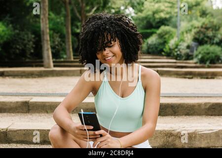 Jeune femme sportive utilisant un smartphone dans le parc Banque D'Images