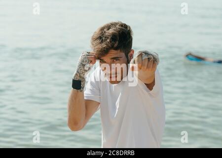 Gros plan du jeune homme pratiquant la boxe en se tenant contre la mer Banque D'Images