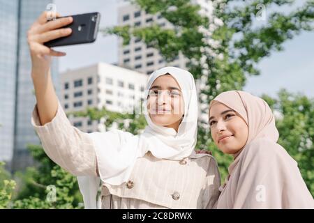 Des sœurs musulmanes qui prennent le selfie par téléphone intelligent en ville Banque D'Images