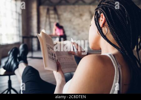 Jeune femme lisant un livre dans un bureau de loft Banque D'Images