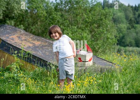 Garçon souriant avec masque sur le bateau abandonné debout au milieu des plantes en forêt Banque D'Images