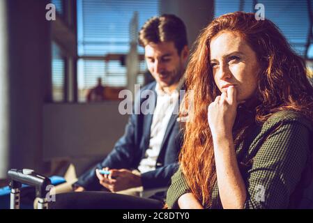 Femme d'affaires attentionnés assise avec un homme dans la zone de départ de l'aéroport Banque D'Images