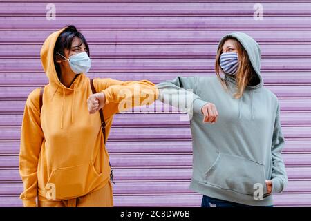 Jeune femme portant des masques saluant avec le coude Banque D'Images