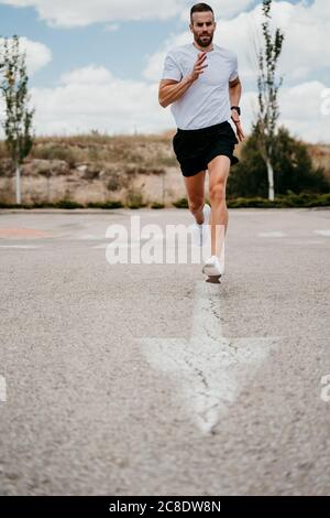 Athlète masculin en train de courir avec le signe de la flèche sur la route Banque D'Images