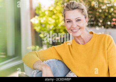 Portrait d'une femme mûre souriante assise sur la terrasse Banque D'Images