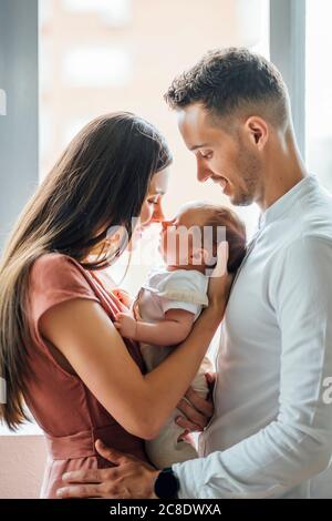 Parents heureux jouant avec bébé garçon par fenêtre à la maison Banque D'Images