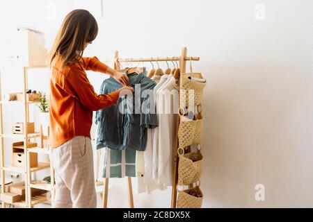 Femme de mode travaillant à la maison avec un porte-vêtements Banque D'Images