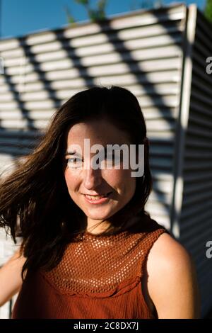 Bonne femme mi-adulte contre l'obturateur pendant la journée ensoleillée Banque D'Images