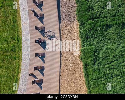 Russie, Tikhvin, Homme avec vélo sur la promenade avec chaises longues, vue aérienne Banque D'Images