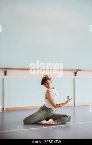 Ballerina faisant des exercices d'étirement sur le sol en studio de danse Banque D'Images