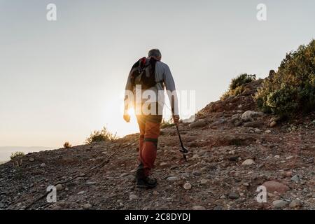 Homme âgé à la retraite en randonnée sur la montagne au coucher du soleil Banque D'Images