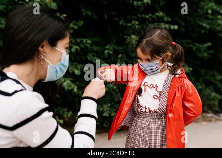 Mère et fille portant des masques tout en jouant des ciseaux de papier de roche sur la rue Banque D'Images