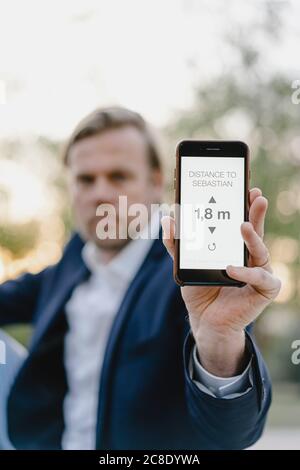 Gros plan sur un homme d'affaires qui tient un smartphone pour afficher la distance Banque D'Images