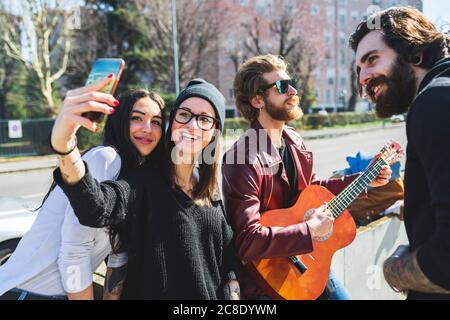 Une jeune femme prend le selfie avec des amis heureux en ville Banque D'Images