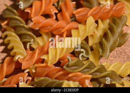 Composition de pâtes crues tricolore fusilli non cuites, forme de torsion des pâtes. Gros plan et attention sélective sur les pâtes fusilli colorées. Pâtes de couleur torsadée Banque D'Images