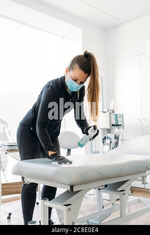 Femme portant un masque désinfectant salon dans la salle d'examen Banque D'Images