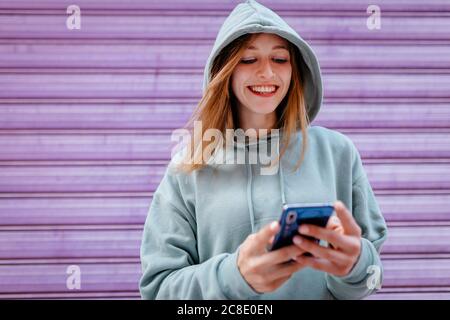 Portrait d'une jeune femme blonde à capuchon vert et violet arrière-plan Banque D'Images
