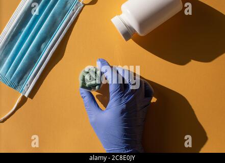 Main avec un gant tenant des casules dans un récipient en plastique Banque D'Images