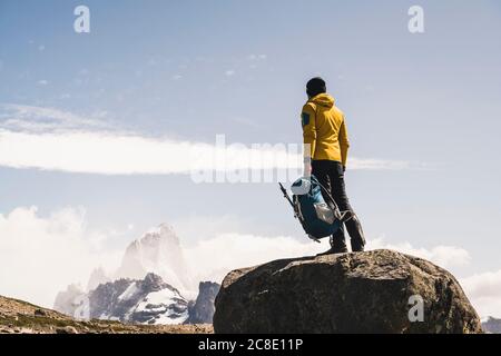 Homme randonneur tenant un sac à dos tout en se tenant sur le rocher contre le ciel, Patagonia, Argentine Banque D'Images