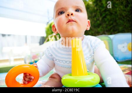 Gros plan de bébé garçon mignon jouant avec des jouets pendant qu'il est assis à la maison Banque D'Images