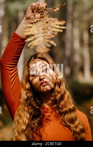 Gros plan d'une belle femme avec de longs cheveux ondulés debout bois Banque D'Images
