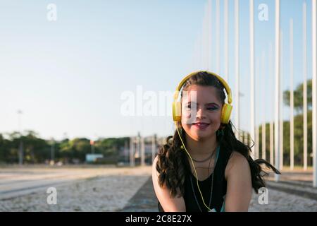 Adolescente avec le syndrome de Down portant 8s coloré maquillage et écouter de la musique avec un casque jaune Banque D'Images