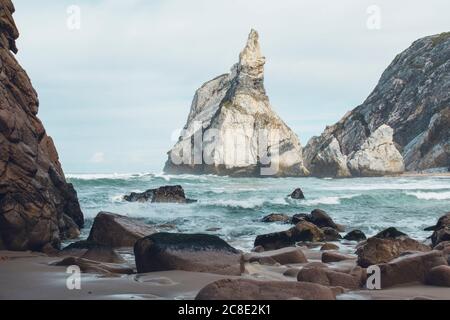 Vue panoramique sur les vagues en mer et les montagnes contre le ciel à la plage d'Ursa, Portugal Banque D'Images