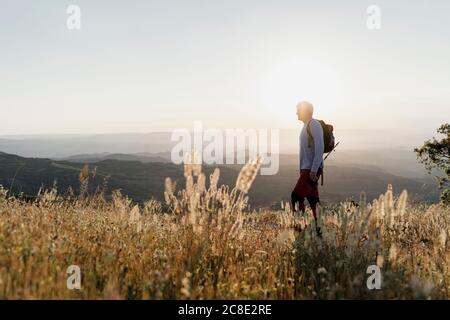 Homme senior debout sur la montagne pendant la randonnée au coucher du soleil Banque D'Images