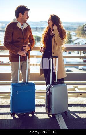 Un couple d'affaires parle en se tenant debout avec ses bagages sur une passerelle surélevée à l'aéroport Banque D'Images