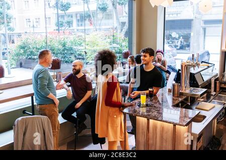 Rendez-vous entre amis dans un restaurant chic, parlant au bar Banque D'Images