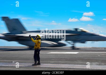 Un membre de l'équipage de la Marine américaine signale un avion de chasse F/A-18e Super Hornet, attaché à l'escadron 115 de chasseurs Eagles of Strike, pour son lancement sur le pont de vol du porte-avions de la classe Nimitz USS Ronald Reagan le 17 juillet 2020 en cours en mer de Chine méridionale. Banque D'Images