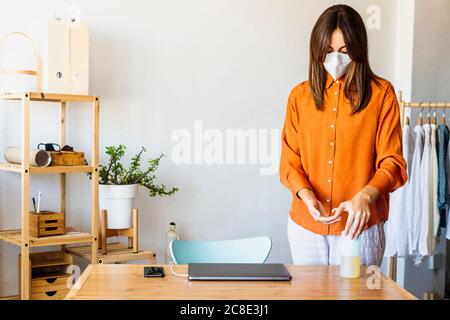 Femme designer de mode travaillant à la maison portant un masque de protection Banque D'Images