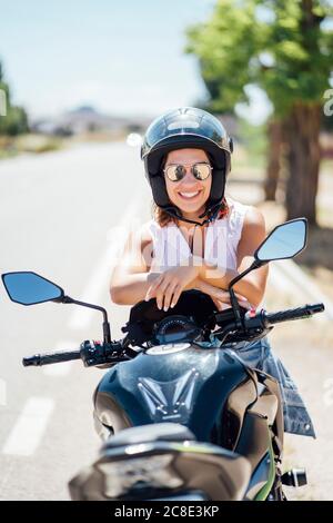 Motard féminin avec lunettes de soleil assis sur une moto Banque D'Images