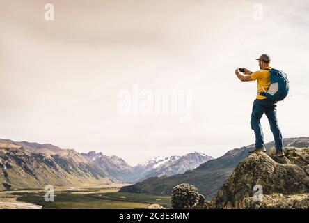 Homme mature photographiant des montagnes avec un smartphone contre le ciel, Patagonia, Argentine Banque D'Images