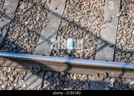 Bouteille d'alcool en verre jetée sur la ligne de chemin de fer. Jeter la bouteille de whisky sur les voies ferrées. Traverses de lestage et de béton. Déchets jetés Banque D'Images