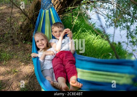 Les enfants adorables se détendent sur un hamac en forêt Banque D'Images