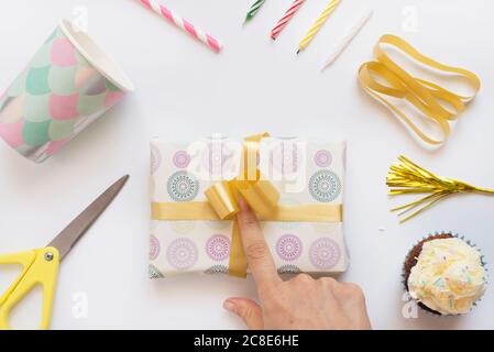 Doigt de femme tenant un noeud de cadeau d'anniversaire emballé Banque D'Images