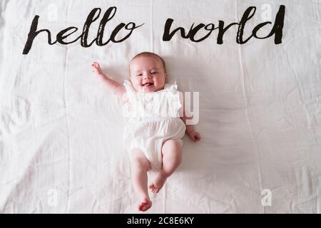 Bonne petite fille mignonne couchée sur une couverture sous Hello World texte à la maison Banque D'Images