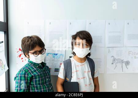 Les écoliers portant des masques contre le mur à l'école Banque D'Images
