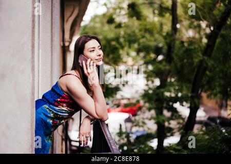 Femme parlant au téléphone tout en se penchant sur les balustrades de balcon Banque D'Images