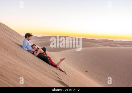 Couple heureux couché dans les dunes au coucher du soleil, Gran Canaria, Espagne Banque D'Images