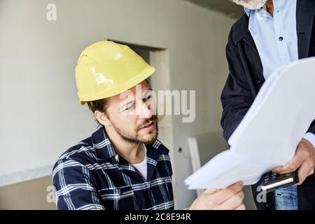 Architecte et travailleur discutant du plan de construction d'un chantier de construction Banque D'Images