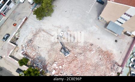 La vue aérienne de la pelle démolit un vieux bâtiment en centre-ville. Le béton détruit est chargé sur le chariot Banque D'Images