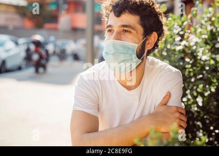 Gros plan d'un jeune homme attentif portant un masque facial assis au café-terrasse Banque D'Images