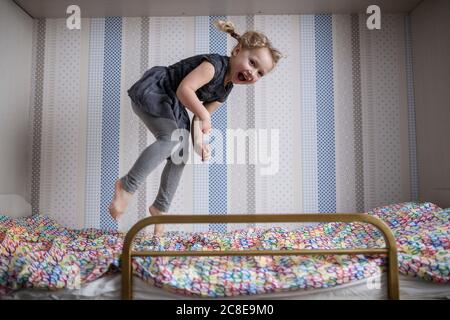 Une jeune fille gaie sautant sur un lit superposé à la maison Banque D'Images