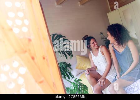 De jeunes amies joyeuses qui parlent dans un cottage vu par la fenêtre Banque D'Images