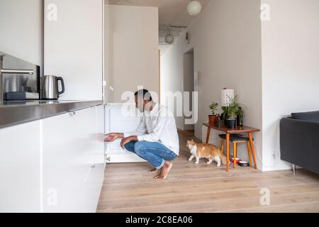 Homme qui se croque dans la cuisine en regardant dans le congélateur Banque D'Images