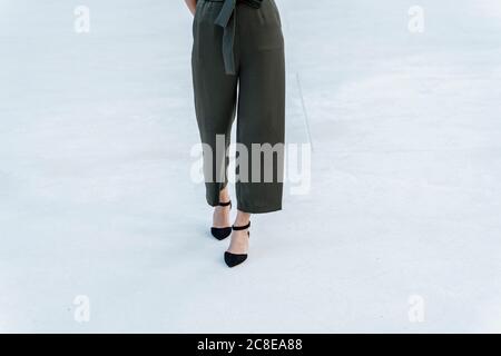 Jambes de femme portant des sandales marchant sur un sol carrelé Banque D'Images